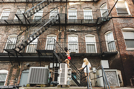 在美国马萨诸塞州波士顿公寓楼消防梯上攀爬的妇女图片