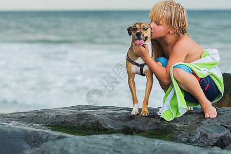 小男孩在海滩的石头上图片
