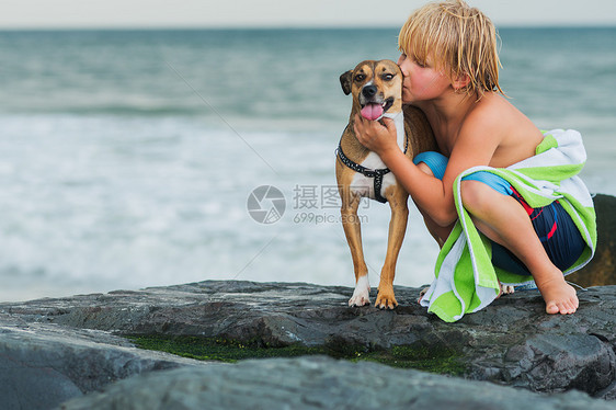 小男孩在海滩的石头上图片