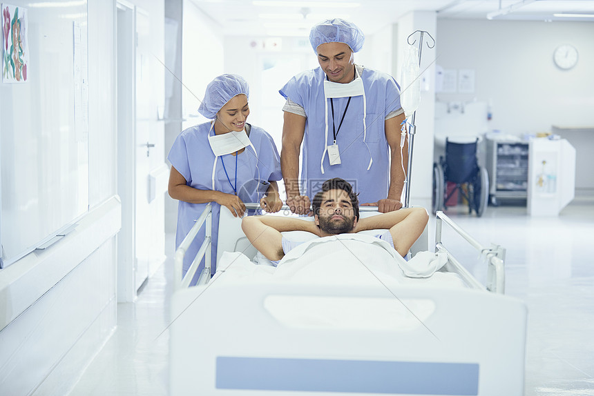在医院走廊上被护士推着的病床上的男青年病人图片