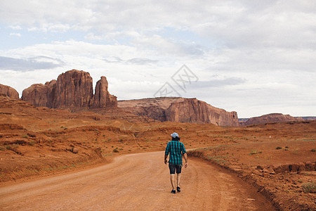 美国亚利桑那州古迹谷沿泥土道行走的年轻人图片