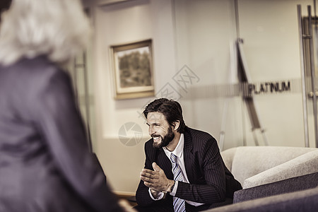男人坐在椅子上与女商人交谈图片