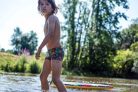 男孩在水中牵着浮板行走图片