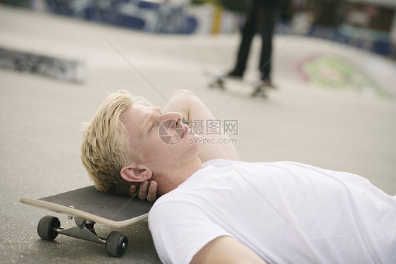 年轻男滑板运动员躺在滑冰场上闭着眼睛图片