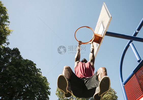 年轻男篮球运动员挂在篮球框上图片