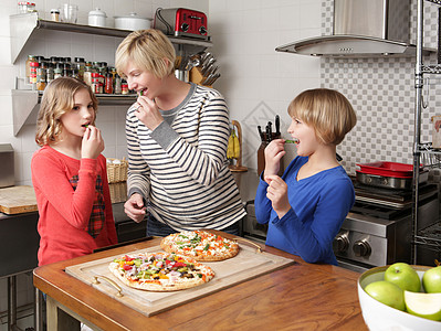 在厨房做饭时母亲和两个女儿在厨房里做饭吃食图片