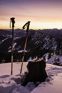 在德国巴伐利亚Oberammergaau的Teufelstattkopf雪山顶上的徒步杆和背包图片