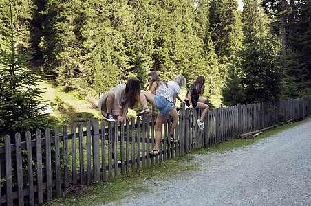 女孩和朋友在森林中攀爬围栏图片