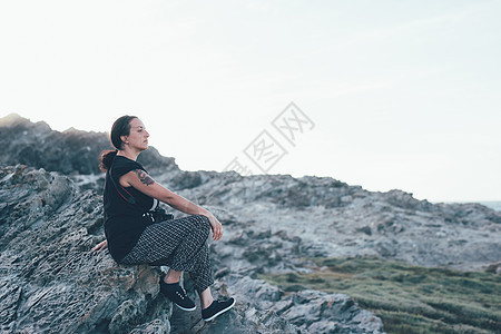 意大利萨萨里斯廷蒂诺坐在岩石上望向别处的女人的侧视图图片