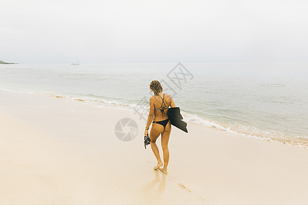 女性在沙滩上拿着脚蹼和泳镜图片
