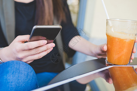 在人行道咖啡厅使用智能手机的年轻女子被剪裁的一图片