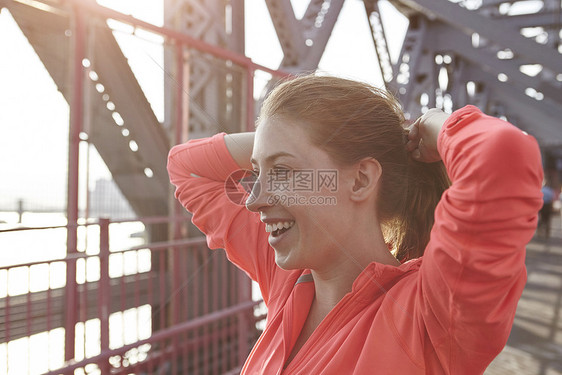 年轻女子在户外双手放在头后微笑图片