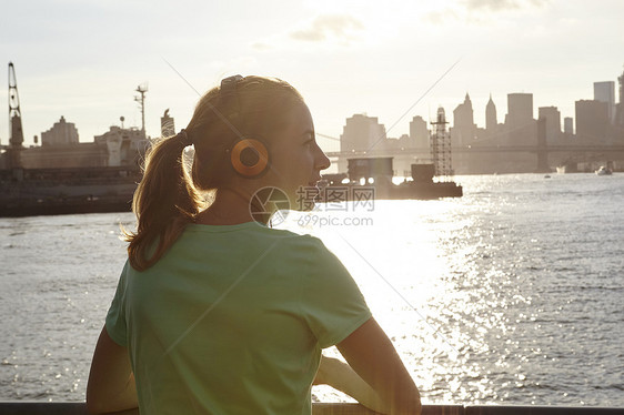 美国纽约州曼哈顿水边戴耳机的妇女图片