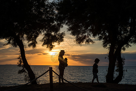 意大利日落时海边母亲和孩子的剪影图片
