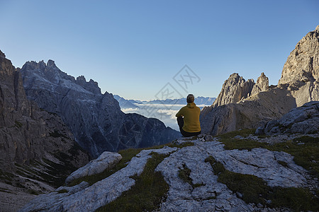 女性徒步旅行者在山顶坐下看风景图片