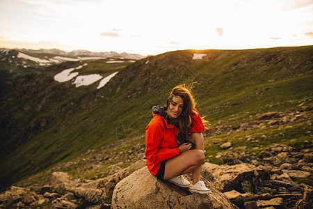 美国科罗拉多州落基山公园一名坐在岩石上微笑的女性图片