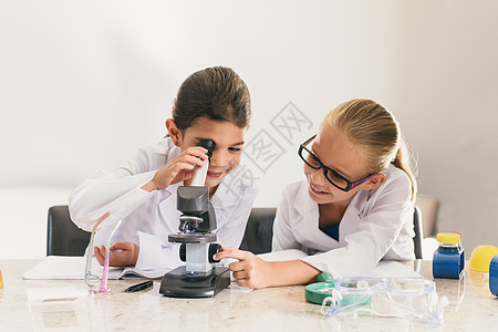 穿实验服的女孩使用显微镜图片