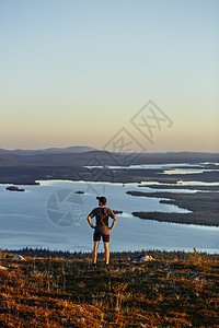 芬兰拉普兰凯米奥通图里日落时分一名男子在悬崖顶上眺望湖面图片