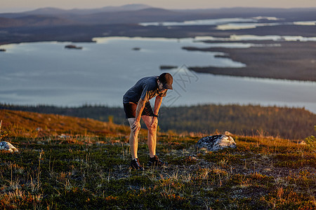 芬兰拉普兰凯米奥通图里日落时分一名男子在悬崖顶上跑步后休息图片