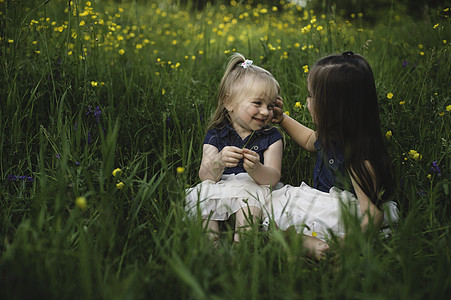 女孩坐在野花草地上面对面微笑图片
