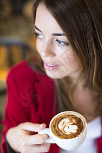 咖啡馆里喝卡布奇诺咖啡的年轻女子图片