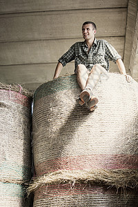 农场谷仓干草堆上年轻男农业工人的肖像图片