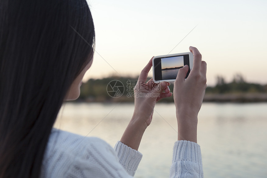 黄昏时拍摄河流的年轻女子图片