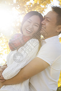 秋天公园里拥抱在一起的的年轻夫妇图片