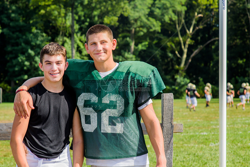 美国足球运动员在比赛场上手搭在朋友的肩上