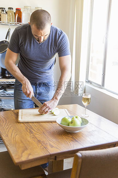 成年男性在厨房桌上切苹果图片