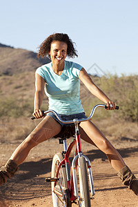 凤凰自行车年轻女子在沙漠骑着自行车微笑背景