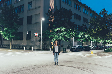 晚上站在城市公路交叉口的年轻女性肖像图片