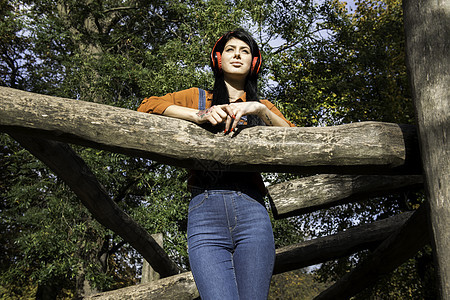站在木攀爬架上戴耳机的年轻女人图片
