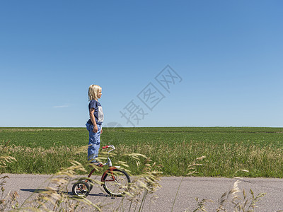 田野里男孩站在自行车上图片