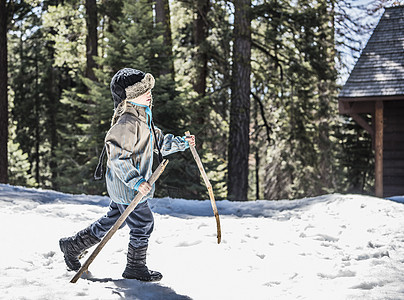 雪地里使用木棍行走的小男孩图片