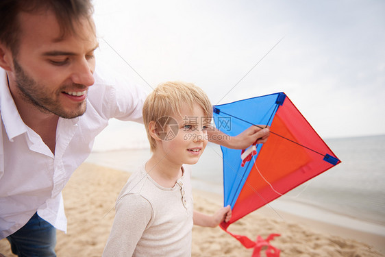 父亲和儿子在海滩玩风筝图片