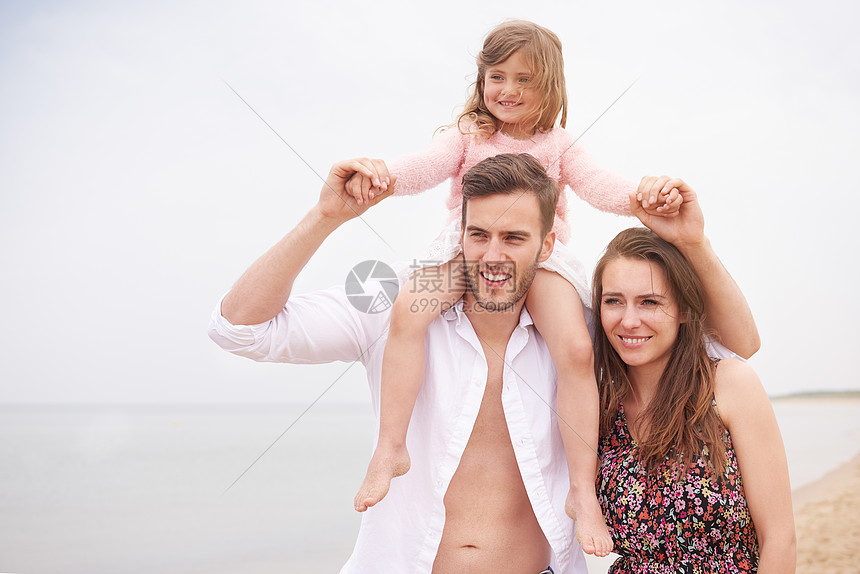 一家人在海滩上散步女儿坐在父亲的肩上女人紧挨着丈夫图片