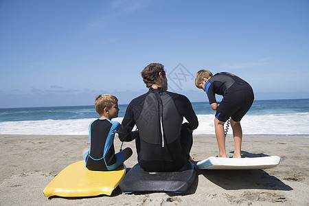 父亲和儿子坐在冲浪板上高清图片