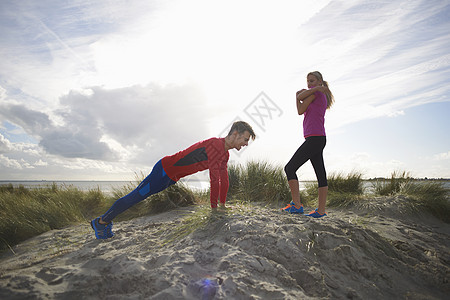 在沙丘上做伸展练习的一对夫妇图片