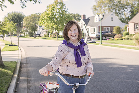 在郊区公路上骑自行车的年轻长妇女肖像图片