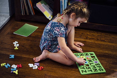 坐在地板上玩字母教学具的女幼儿图片