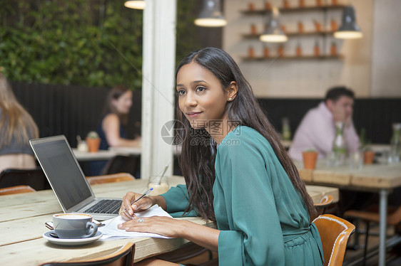 妇女在咖啡厅桌旁做文书工作时看望着妇女图片