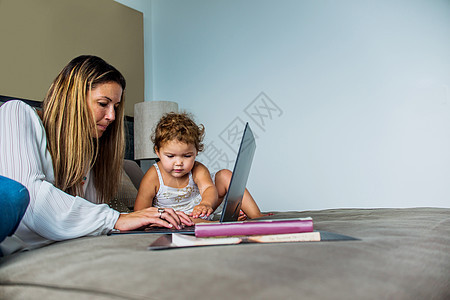 母亲与女儿在床上使用笔记本电脑图片