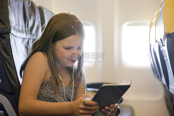 年轻女孩在飞机上使用数字平板电脑图片