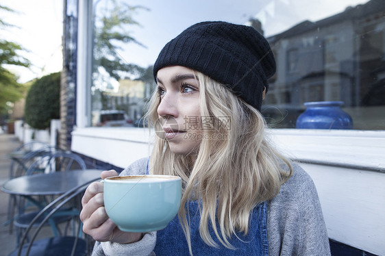 坐在咖啡馆外喝咖啡的年轻女子图片