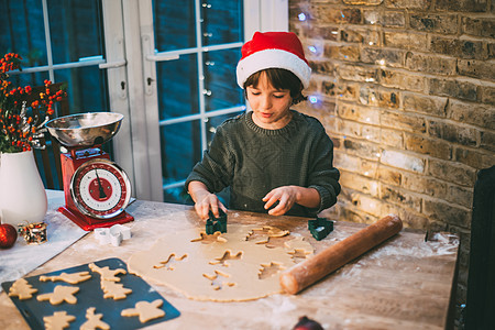 戴圣诞帽的男孩在厨房准备圣诞饼干图片