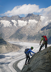 在瑞士瓦利斯州冰川上爬山脊的一对夫妇图片