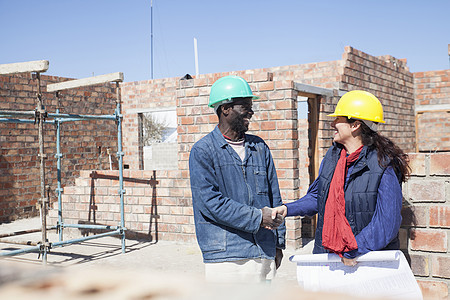 建筑工地上的妇女和建筑工人握手图片