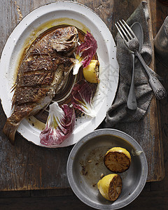餐盘上的烤鱼和柠檬图片