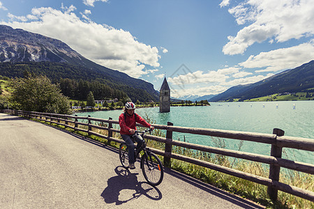 意大利南蒂罗尔山谷湖边骑自行车的女性图片